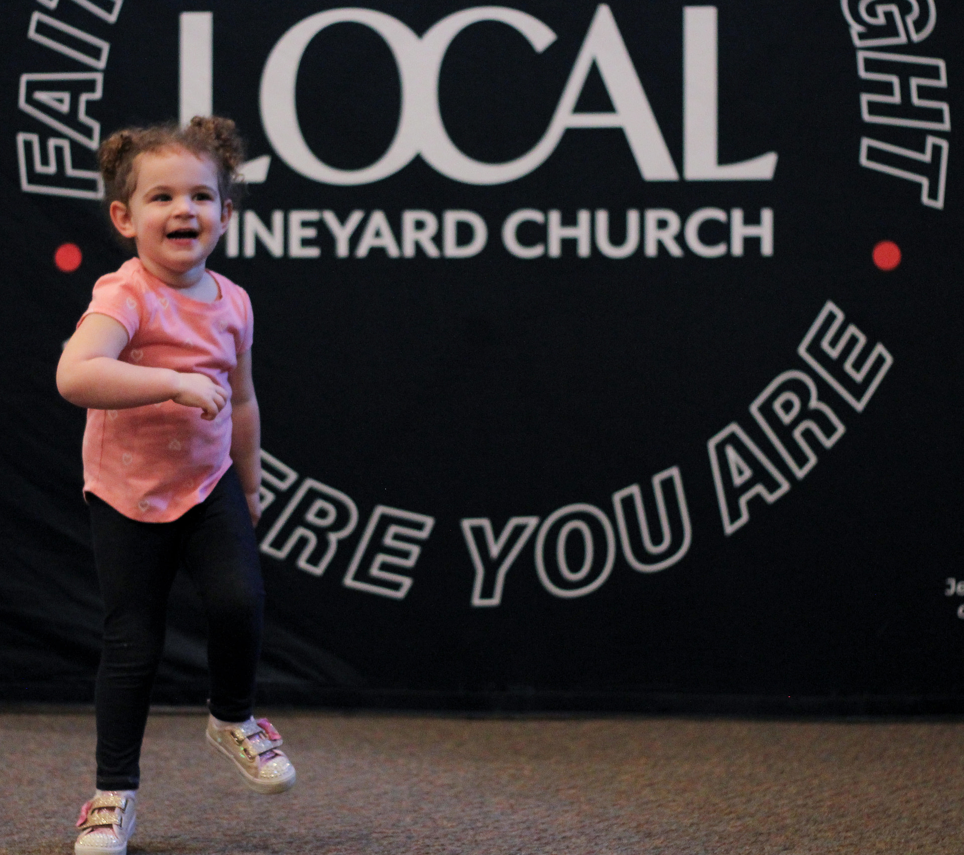 little girl having fun in front of a Local Vineyard Church in midlothian sign